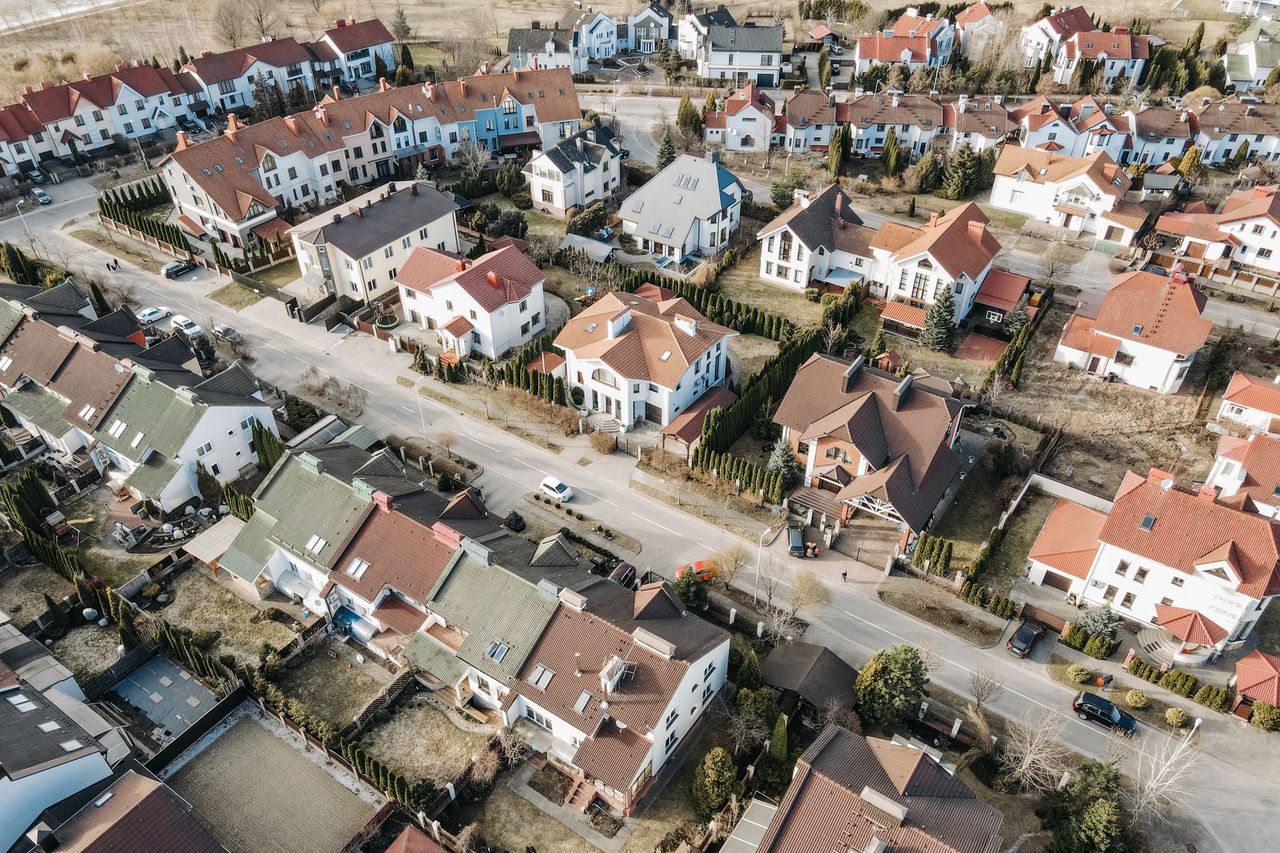 Drone view of a suburban residential area with houses and streets in daylight.